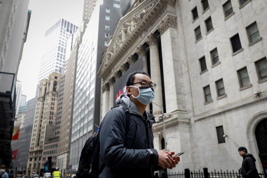 FILE PHOTO: A man wears a mask on Wall St. near the New York Stock Exchange (NYSE) in New York, U.S., March 3, 2020. REUTERS/Brendan McDermid/File Photo