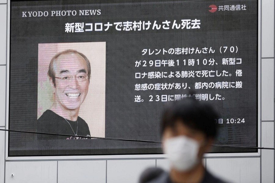 A man wearing a protective face mask, following an outbreak of the coronavirus disease (COVID-19), walks past in front of a huge screen reporting death of Japanese comedian Ken Shimura, who had been hospitalised after being infected with the new coronavirus, in Osaka, western Japan, March 30, 2020, in this photo taken by Kyodo. — Mandatory credit Kyodo/via Reuters