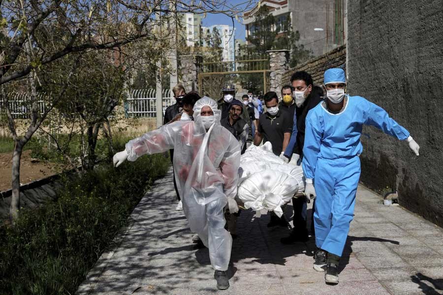 People, wearing protective clothing, carrying the body of a victim who died after being infected with the coronavirus at a cemetery just outside Tehran, Iran on Monday –AP Photo