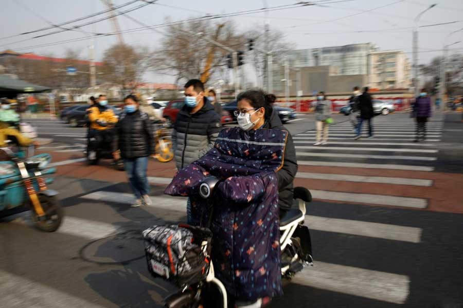 People wearing face masks riding their scooters and walk on a street following an outbreak of the coronavirus disease, in Beijing of China on Monday. –Reuters Photo