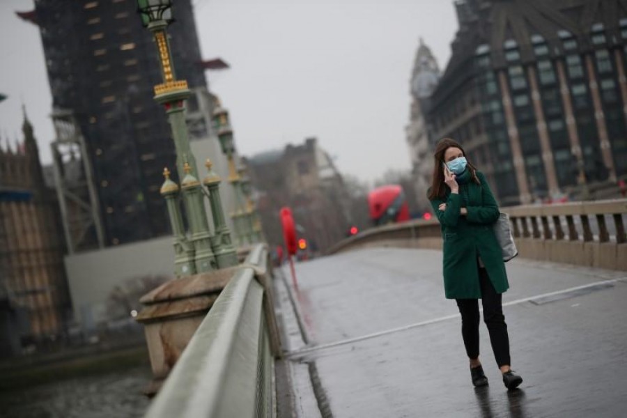 FILE PHOTO: A woman on Westminster bridge wearing a protective face mask as the spread of the coronavirus disease (COVID-19) continues, in London, Britain, March 19, 2020. REUTERS/Hannah McKay/File Photo