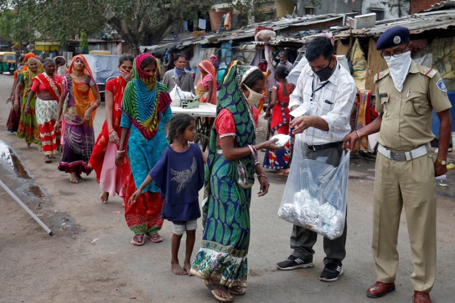 Slum dwellers in Ahmedabad receive free food packets during a 21-day nationwide lockdown - Amit Dave/Reuters