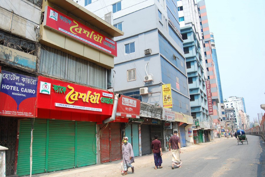 Pedestrians walk past closed shops and restaurants during a shutdown enforced by the government as a preventive measure against the coronavirus outbreak at Topkhana Road in Purana Paltan, Dhaka — Focus Bangla photo