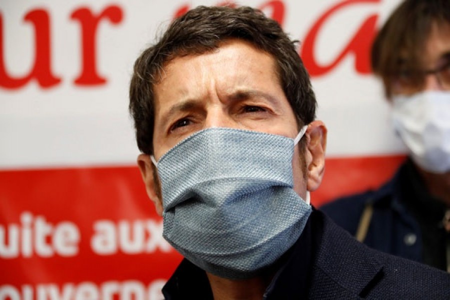 Cannes Mayor David Lisnard, wearing a protective face mask, talks to the media as an employee checks the temperature of visitors at the entrance of a Carrefour market in Cannes as the spread of the coronavirus disease (COVID-19) continues in France, Apr 8, 2020. REUTERS