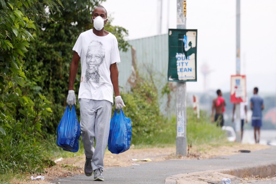 A man carries home groceries during a nationwide lockdown in an attempt to contain the coronavirus disease (COVID-19) outbreak in Umlazi township near Durban, South Africa [Rogan Ward/Reuters]