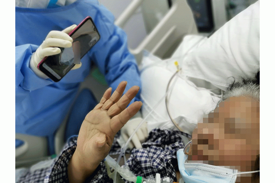 An elderly female COVID-19 patient communicating with her family members via phone video under the help of a medical worker at the Huoshenshan Hospital in Wuhan, central China's Hubei Province, April 2, 2020. (Photo by Gao Xiang/Xinhua)