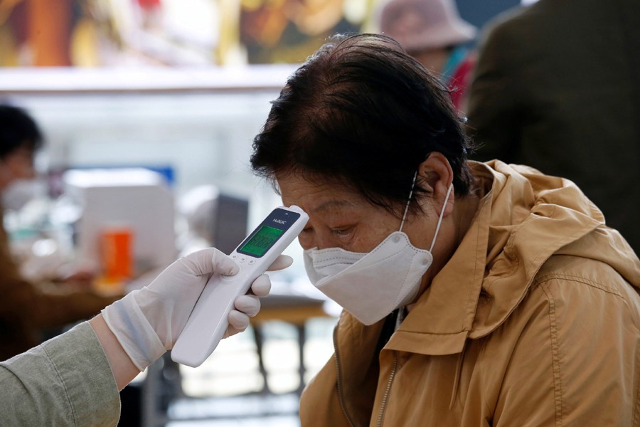 A woman wearing a preventive face mask has her temperature checked, as a safety measure to prevent the further spread of the coronavirus, before casting a ballot for parliamentary elections at a polling station in Seoul, South Korea on April 10, 2020 — Reuters/Files