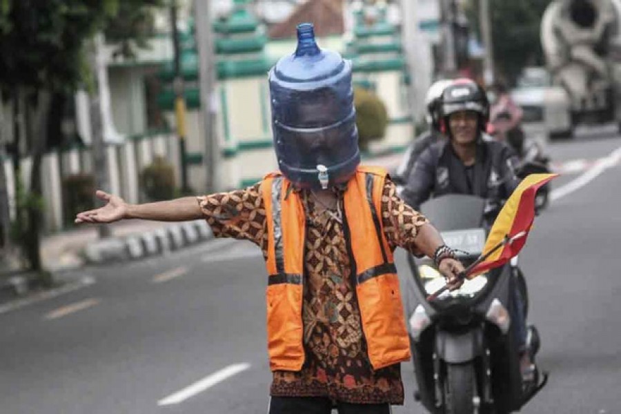 Ali Akbar, 52, a parking attendant, uses a plastic bottle for a face mask amid the coronavirus disease (COVID-19) outbreak in Yogyakarta, Indonesia, Apr 15, 2020.  REUTERS