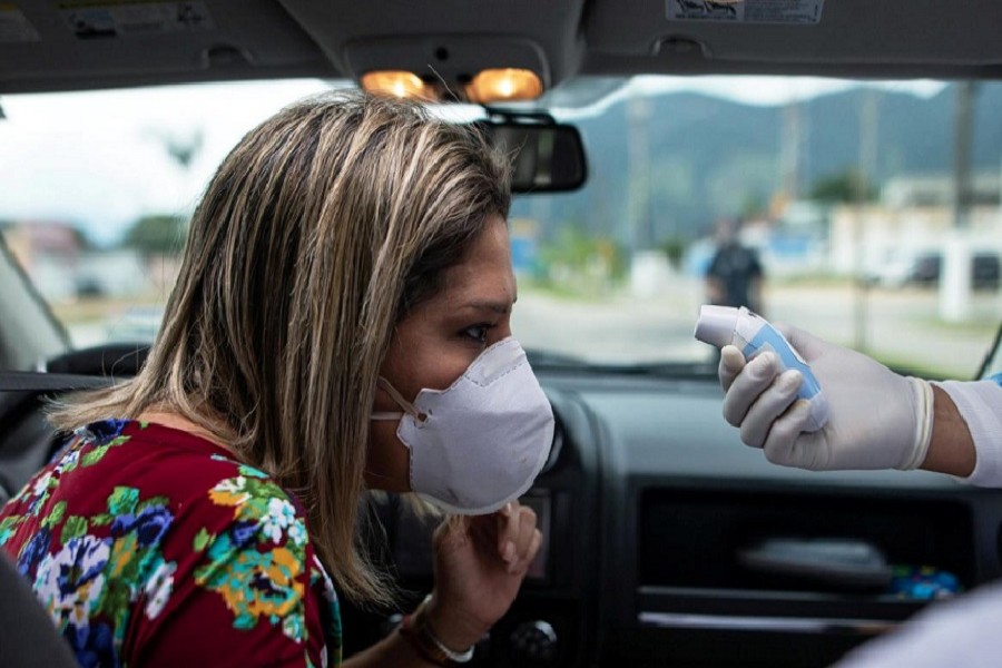 A health worker controls the temperature of a woman in a sanitary barrier during the coronavirus disease (COVID-19) outbreak, in Sao Sebastiao, Sao Paulo state, Brazil, April 18, 2020. — Reuters