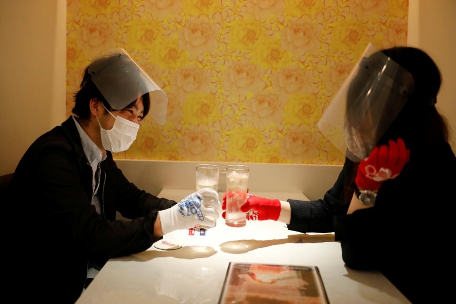 Customers wearing protective masks, face-shields and gloves to prevent infections following the coronavirus disease (COVID-19) outbreak, toast glasses at the cheerleader-themed restaurant 'Cheers One' in Tokyo, Japan May 11, 2020. REUTERS/Kim Kyung-Hoon
