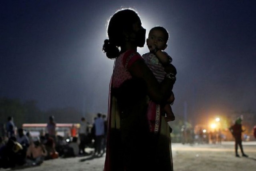A woman and her baby wait for a bus to take them to a railway station to board a train to their home state of Uttar Pradesh, after a limited reopening of India's giant rail network following a nearly seven-week lockdown to slow the spreading of the coronavirus disease (COVID-19), in Ghaziabad in the outskirts of New Delhi, India, May 18, 2020. — Reuters