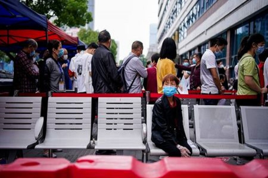 A woman wearing a face mask looks on in front of others standing in a queue for nucleic acid testings in Wuhan, the Chinese city hit hardest by the coronavirus disease, on May 16, 2020. — Reuters/Files