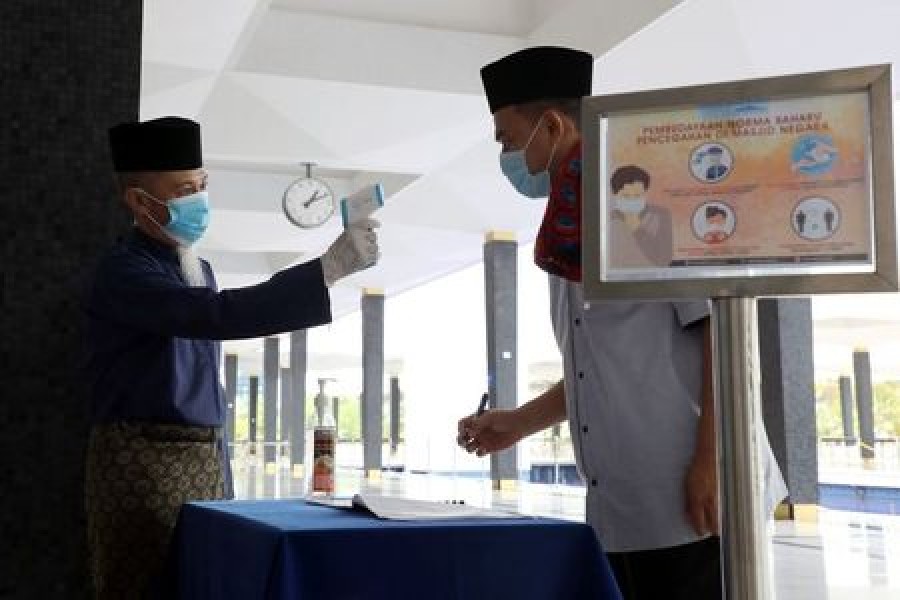 A worker takes the temperature of a man at the National Mosque entrance as Malaysia eases a ban on mass prayers in mosques, amid the coronavirus disease (COVID-19) outbreak, in Kuala Lumpur, Malaysia, May 15, 2020. — Reuters