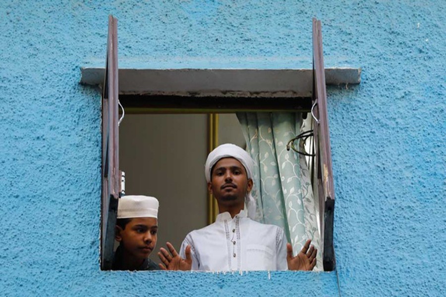    Muslim boys look out from the window of their house during Eid al-Fitr, the Muslim festival marking the end of the holy fasting month of Ramadan, amid the spread of the coronavirus disease (Covid-19), in the old quarters of Delhi, India, May 25, 2020. REUTERS