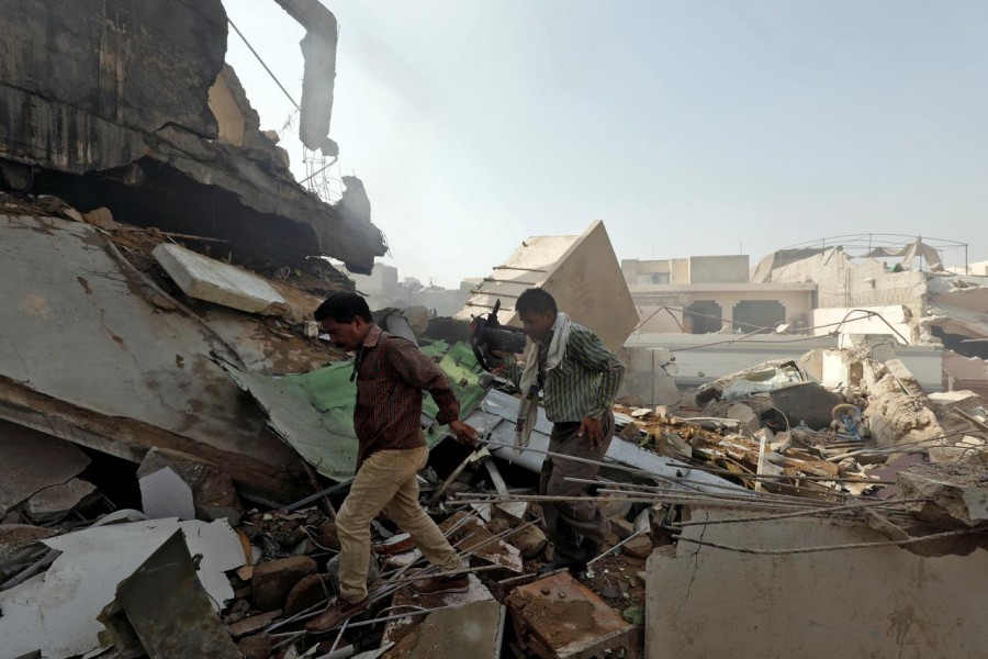 Men walk on the debris at the site of a passenger plane crash in a residential area near an airport in Karachi, Pakistan on May 22, 2020 — Reuters photo