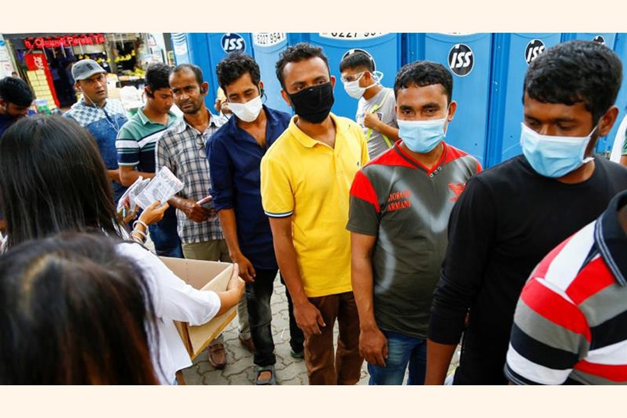 Migrant workers, mostly from Bangladesh, queue to collect free masks and get their temperatures taken in Singapore                  — Reuters