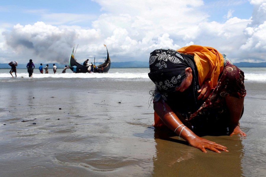 An exhausted Rohingya refugee woman touches the shore after crossing the Bangladesh-Myanmar border by boat through the Bay of Bengal in Shah Porir Dwip, Bangladesh on September 11, 2017 — Reuters/Files