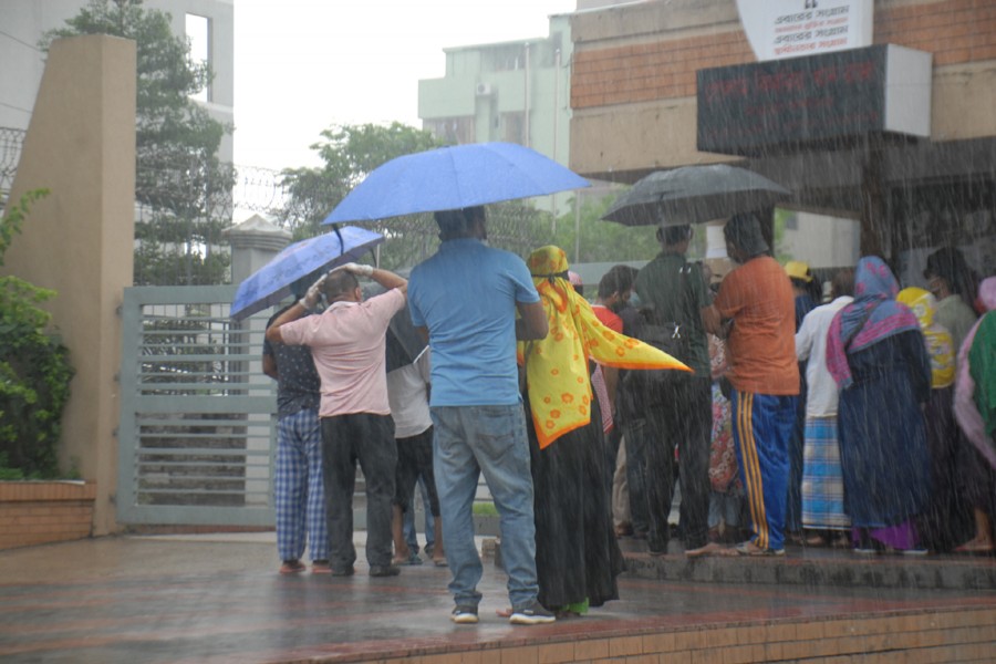 People shield themselves from the rain with umbrellas as they wait outside Mugda Genral Hospital to get tested for the coronavirus (Covid-19) disease — File photo