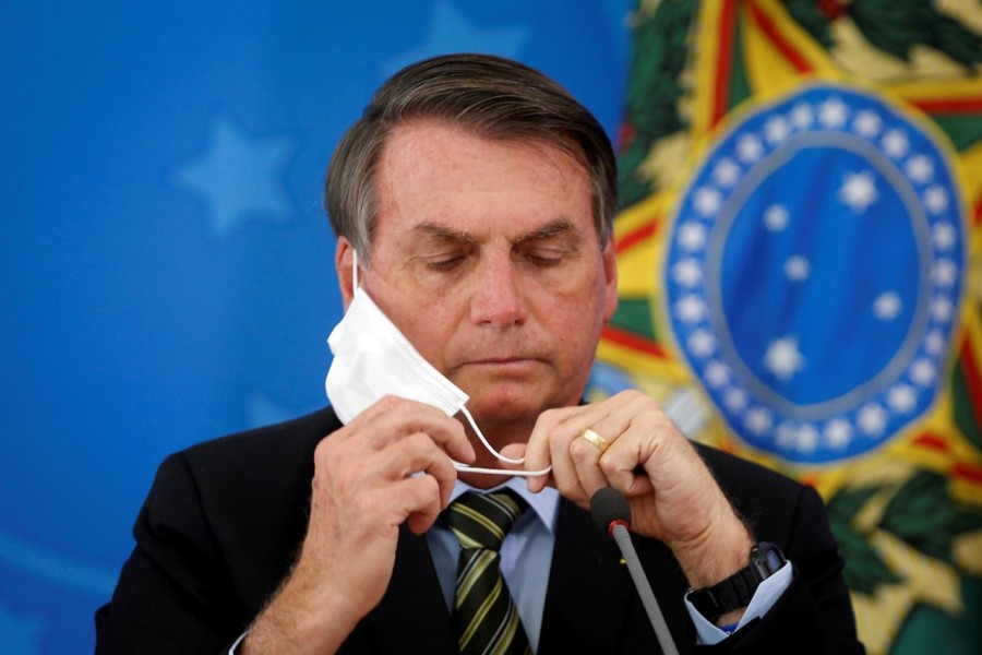 Brazil's President Jair Bolsonaro adjusts his protective face mask during a press statement to announce federal judiciary measures to curb the spread of the coronavirus disease (COVID-19) in Brasilia, Brazil March 18, 2020. Picture taken March 18, 2020. REUTERS/Adriano Machado