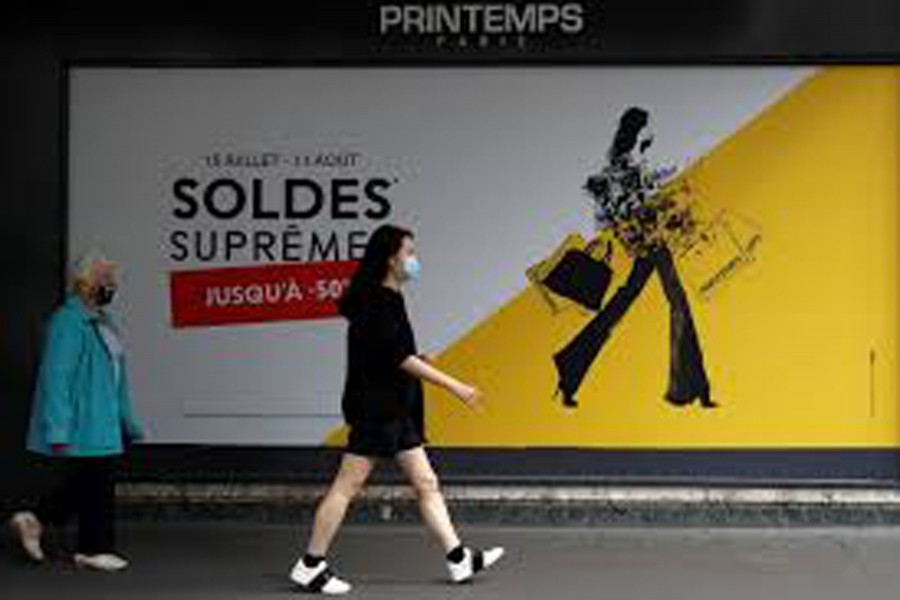 Women, wearing protective face masks, walk past the department store Le Printemps Haussmann decorated with a discount sign in Paris on the first day of summer sales following the outbreak of the coronavirus disease (COVID-19) in France, July 15, 2020. REUTERS/Gonzalo Fuentes