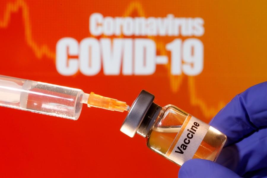 A small bottle labelled with a "Vaccine" sticker is held near a medical syringe in front of displayed "Coronavirus COVID-19" words in this illustration taken on April 10, 2020 — Reuters/Files