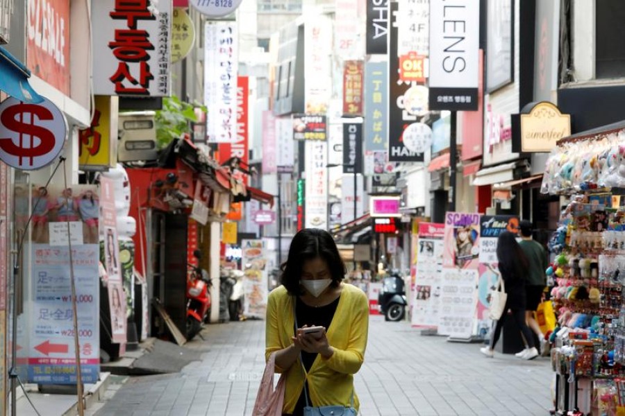 A woman wearing a mask looks at her mobile phone amid social distancing measures to avoid the spread of the novel coronavirus, in Myeongdong shopping district in Seoul, South Korea, May 28, 2020. REUTERS/Kim Hong-Ji//File Photo