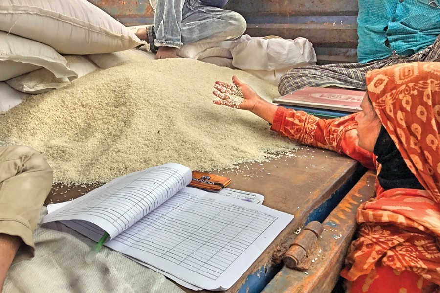 A consumer checks the quality of rice put on sale at an open-market sale (OMS) centre at Jurain in Old Dhaka— FE/Files
