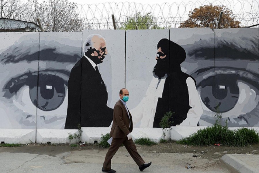 An Afghan man wearing a protective face mask walks past a wall painted with photo of Zalmay Khalilzad, US envoy for peace in Afghanistan, and Mullah Abdul Ghani Baradar, the leader of the Taliban delegation, in Kabul, Afghanistan, April 13, 2020 — Reuters/Files