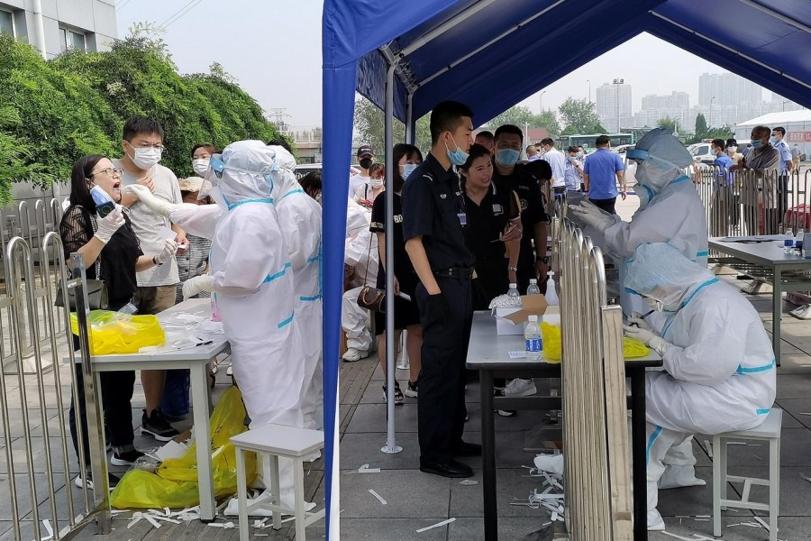 People line up at a testing site where medical workers in protective suits collect swabs for nucleic acid tests, after new cases of coronavirus disease (Covid-19) were confirmed in Dalian, Liaoning province, China on July 24, 2020 — China Daily via REUTERS