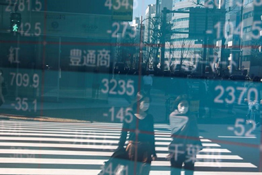 People wearing protective face masks, following an outbreak of the coronavirus, are reflected on a screen showing Nikkei index, outside a brokerage in Tokyo, Japan, February 28, 2020 — Reuters/Files