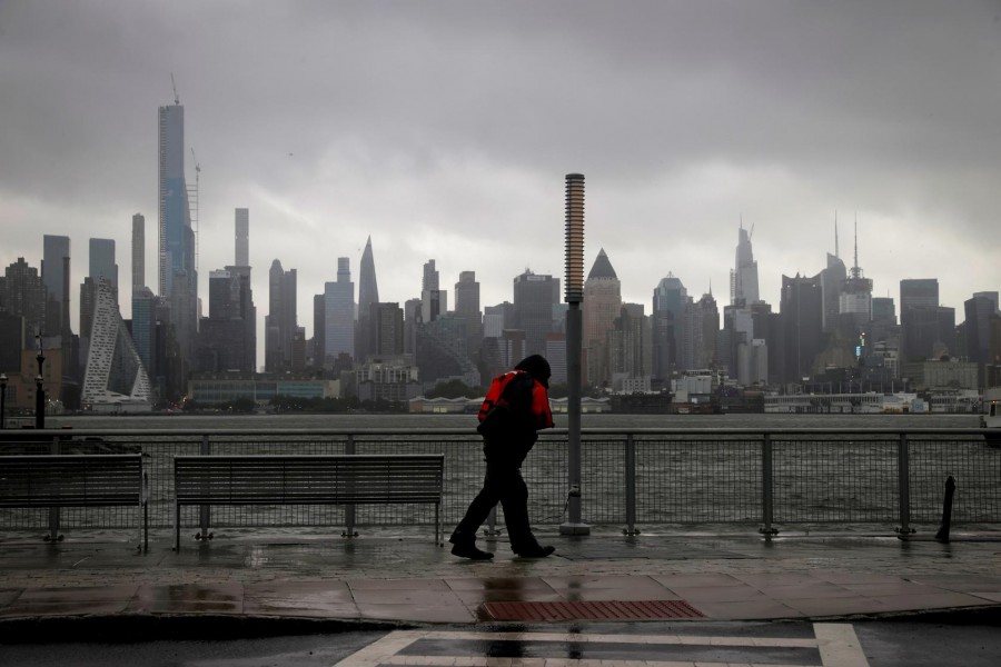 A man walks into heavy wind and rain along the waterfront of the Hudson River in front of the New York City skyline during Tropical Storm Isaias in Weehawken, New Jersey, US, August 4, 2020. REUTERS/Mike Sega