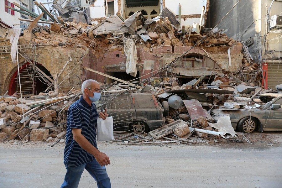 A man walks past damaged building and vehicles near the site of Tuesday's blast in Beirut's port area, Lebanon August 5, 2020. REUTERS/Aziz Taher