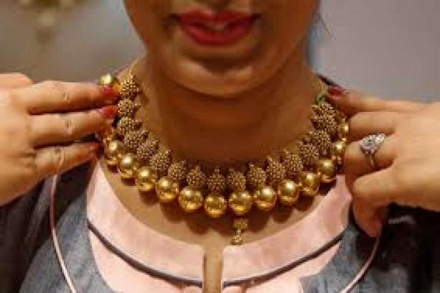 A saleswoman displays a gold necklace to a customer inside a jewellery showroom in Mumbai, India, April 18, 2018 — Reuters/Files
