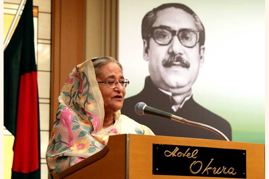 Prime Minister Sheikh Hasina at a reception in Japan last year with the portrait of Father of the Nation  Bangabandhu Sheikh Mujibur Rahman in the background 	— Website of Bangladesh Awami League