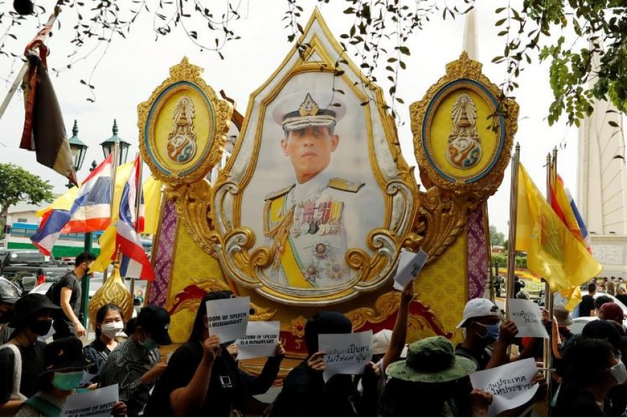 Pro-democracy protesters holding signs walk past a picture of Thai King Maha Vajiralongkorn during a rally to demand the government to resign, to dissolve the parliament and to hold new elections under a revised constitution, near the Democracy Monument in Bangkok, Thailand, August 16, 2020. REUTERS/Jorge Silva