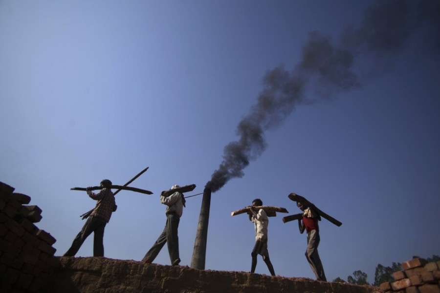 In this June 4, 2011 file photo, Indian labourers carry firewood, as smoke rises from a bricks factory on the outskirts of Jammu, India — AP/Files