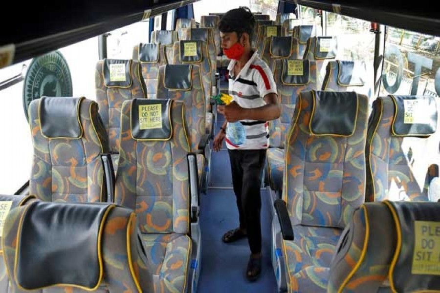 A man wearing a protective face mask disinfects seats of an air-conditioned passenger bus after Gujarat state authorities resumed the bus services after easing lockdown restrictions that were imposed to slow the spread of the coronavirus disease (Covid-19), in Ahmedabad, India, August 27, 2020. REUTERS/Amit Dave