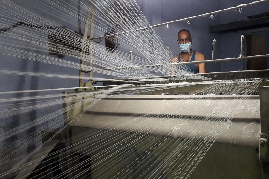 A worker wearing a protective face mask works on a loom in a textile factory, amidst the coronavirus disease (COVID-19) outbreak, in Meerut, India, July 7, 2020. REUTERS/Manoj Kumar/File Photo