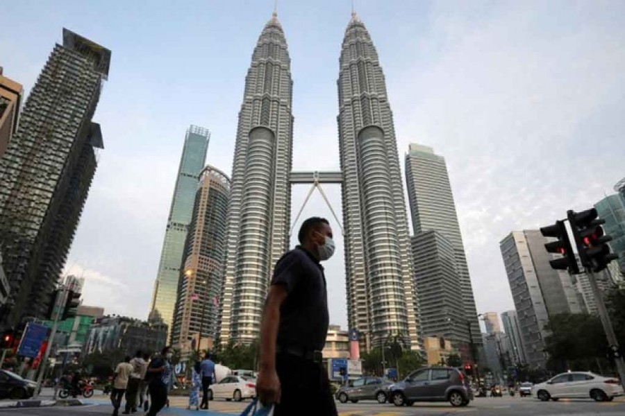 A man wearing a protective mask crosses a street in front of Petronas Twin Towers, amid the coronavirus disease (COVID-19) outbreak in Kuala Lumpur, Malaysia Aug 11, 2020. REUTERS