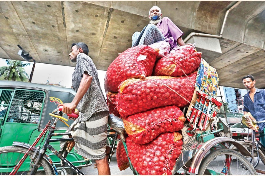 A retailer, sitting on a stack of onion sacks in a rickshaw, going to Mohakhali kitchen market after buying the essential item from Shyambazar wholesale market in Dhaka on Tuesday. The photo was shot in the capital's Maghbazar area — FE photo by KAZ Sumon