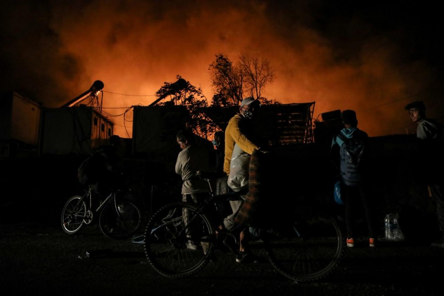 Refugees and migrants carry their belongings as they flee from a fire burning at the Moria camp on the island of Lesbos, Greece, September 9, 2020. REUTERS/Elias Marcou