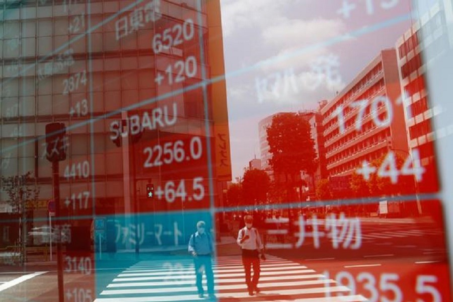 People wearing protective masks, following the coronavirus disease (Covid-19) outbreak, are reflected on a screen showing stock prices outside a brokerage in Tokyo, Japan, August 31, 2020 — Reuters/Files