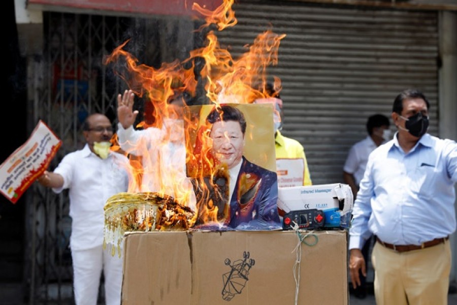 Demonstrators burn products made in China and a defaced poster of Chinese President Xi Jinping during a protest against China, in New Delhi, India, June 22, 2020. Reuters