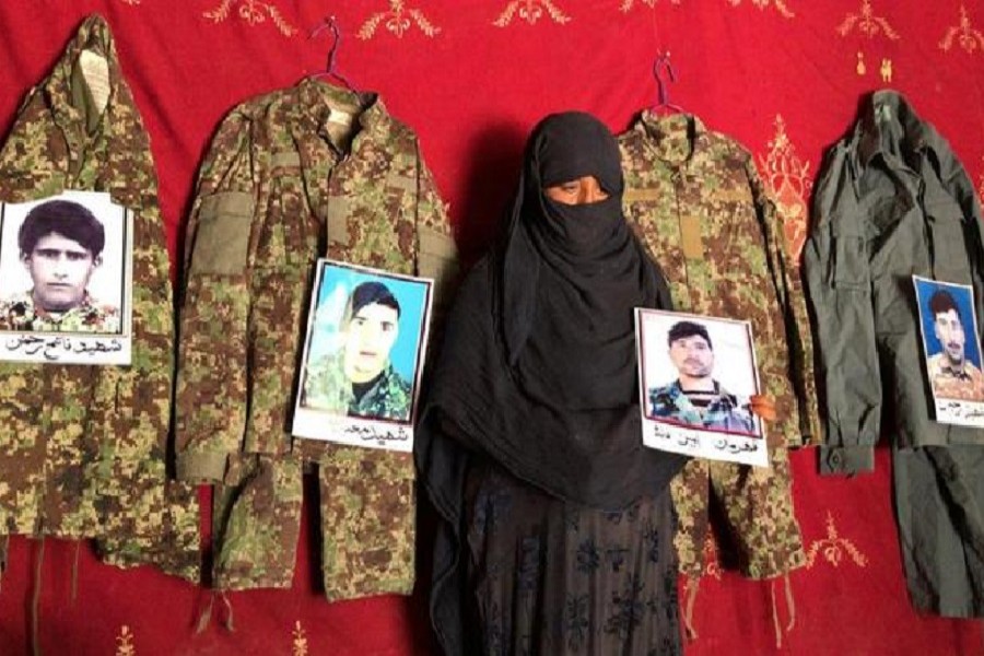 Taj Bibi 33, holds a photo of her husband next to the military uniforms and pictures of her former husbands who were killed battling the Taliban, at her home in Asad Abad, Kunar province, Afghanistan, September 20, 2020 — Reuters