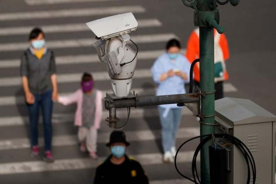 ILE PHOTO: A CCTV security surveillance camera overlooks a street as people walk following the spread of the coronavirus disease (COVID-19) in Beijing, China May 11, 2020. REUTERS/Thomas Peter