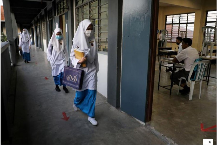 FILE PHOTO: Students wearing masks walk past a classroom at a secondary school, as schools reopen amid the coronavirus disease (COVID-19) outbreak, in Shah Alam, Malaysia June 24, 2020. REUTERS/Lim Huey Teng/File Photo