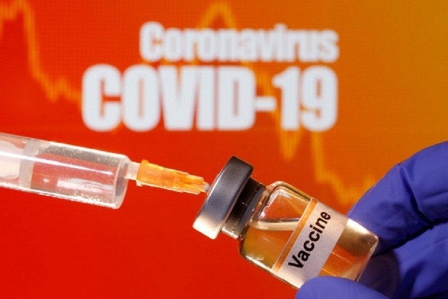 A small bottle labelled with a "Vaccine" sticker is held near a medical syringe in front of displayed "Coronavirus COVID-19" words in this illustration taken on April 10, 2020 — Reuters/Files