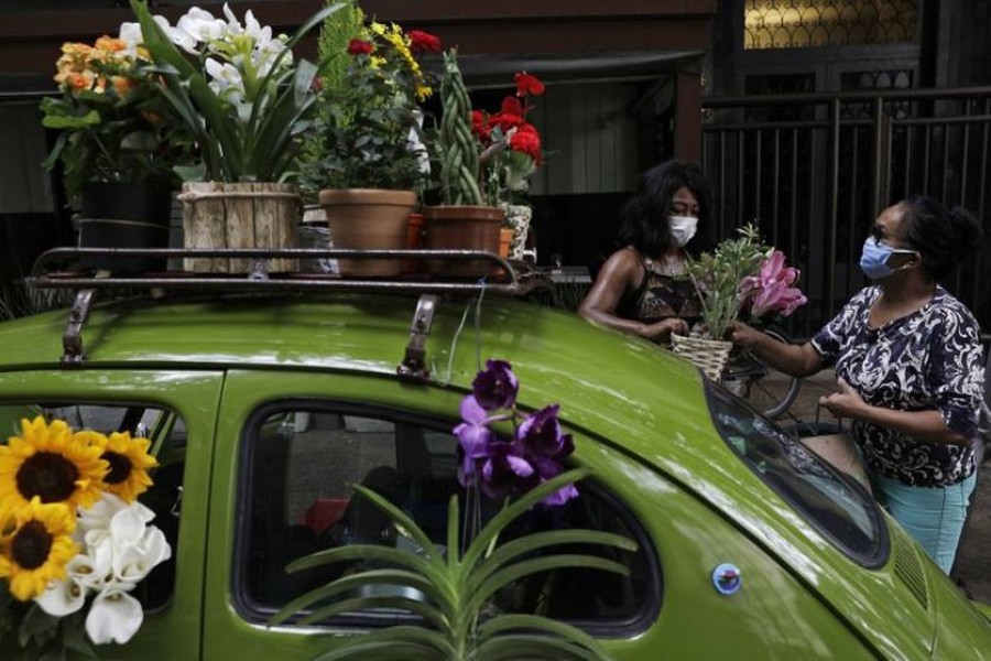 Valcineia Machado, also known as Roberta, sells flowers to a customer next to her car which she transformed to a mobile flower shop after loosing her business amid the coronavirus disease (Covid-19) outbreak, in Rio de Janeiro, Brazil on October 8, 2020 — Reuters photo