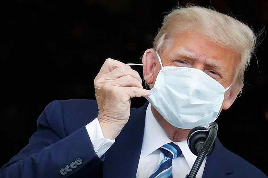 US President Donald Trump, with bandages seen on his hand, taking off his face mask as he comes out on a White House balcony to speak to supporters gathered on the South Lawn for a campaign rally that the White House is calling a "peaceful protest" in Washington, US, on Saturday –Reuters Photo