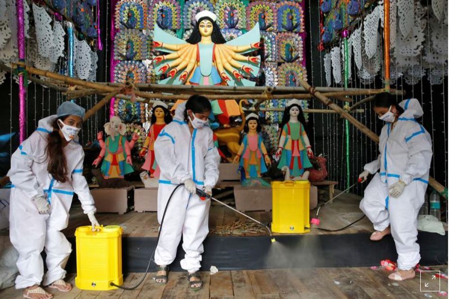 Women wearing personal protective equipment (PPE) sanitize a "pandal" or a temporary platform, ahead of Durga Puja festival, amidst the spread of the coronavirus disease (COVID-19), in Kolkata, India, October 16, 2020. REUTERS/Rupak De Chowdhuri